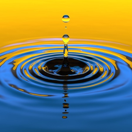 a water drop rippling out. with yellow sunshine reflecting on the top of the water